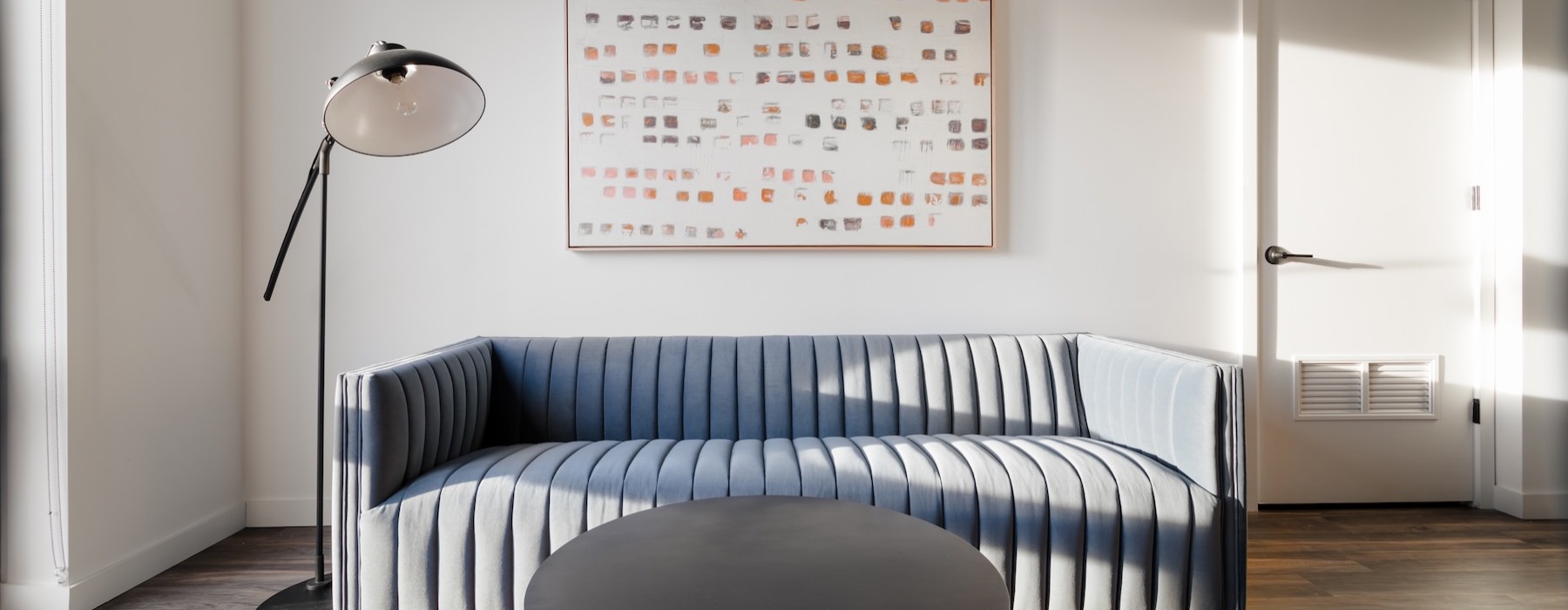 a living room with a couch, coffee table and a lamp